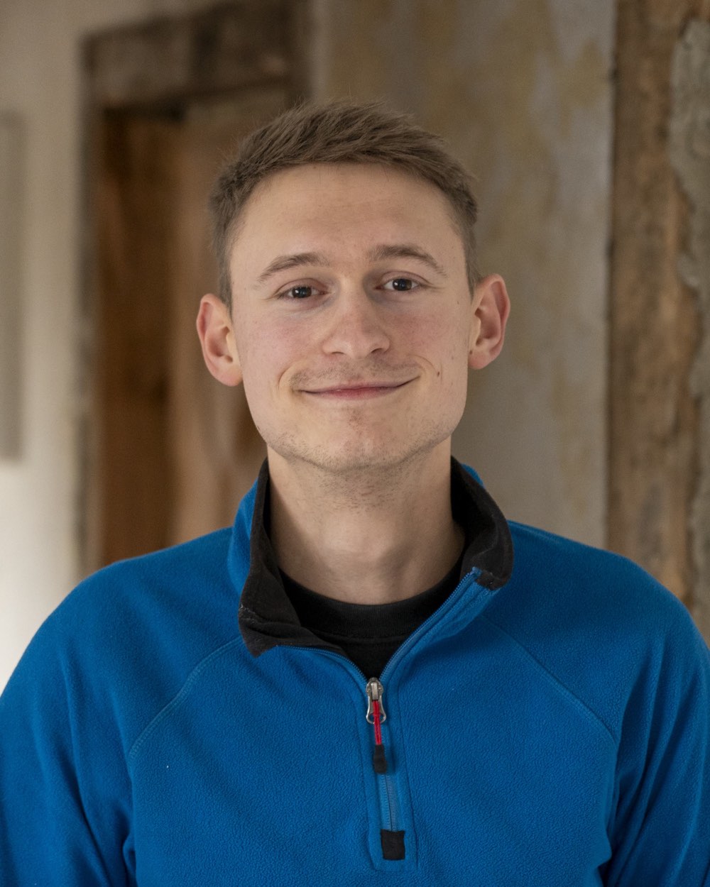 Ben Hoffmann in blauer Arbeitsjacke, im Hintergrund ein entkernter Altbauflur