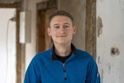 Ben Hoffmann in einem entkernten Altbauraum, im Hintergrund freigelegte Wände