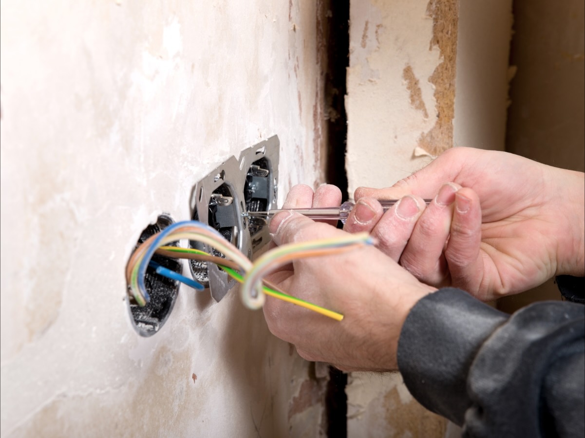 Eine Unterputzdose wird verdrahtet, die Adern liegen sortiert in der Wand