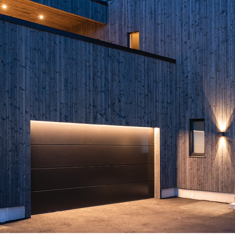 Hausfassade nachts, Up-Down-Leuchten neben dem Garagentor