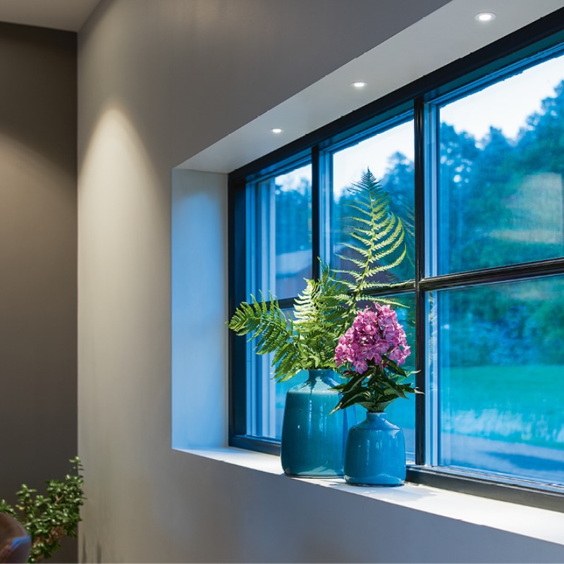 Wohnraum mit Einbauspots in der abgehängten Decke über der Fensterbank