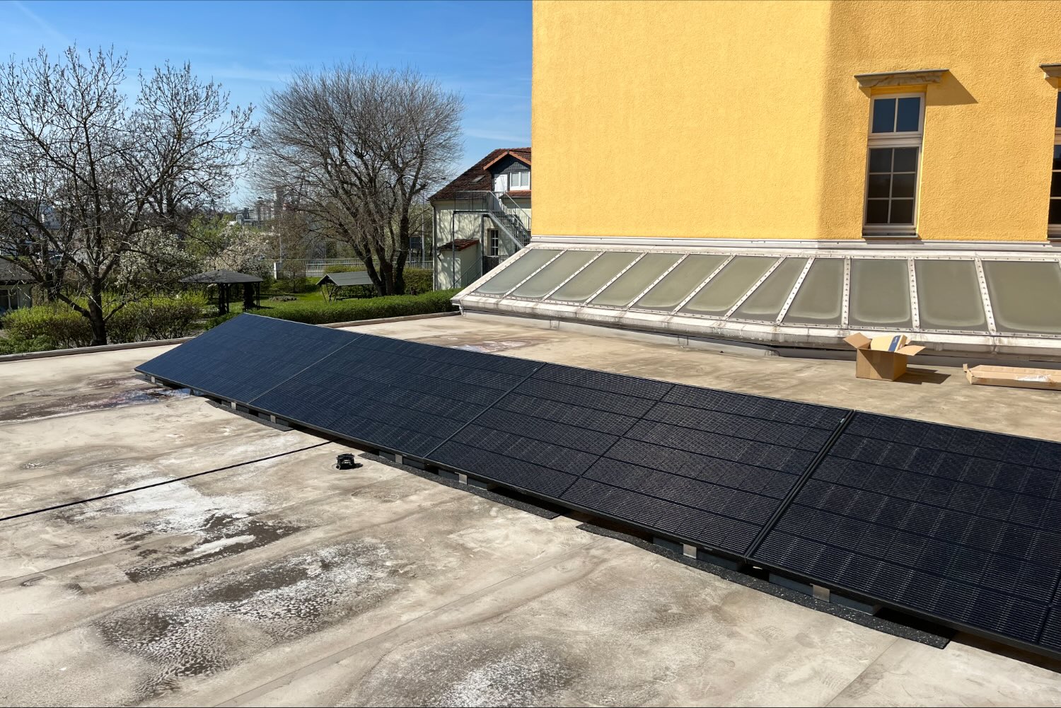 Aufgeständerte Photovoltaikmodule auf einem Flachdach in Dresden, dahinter ein Altbau