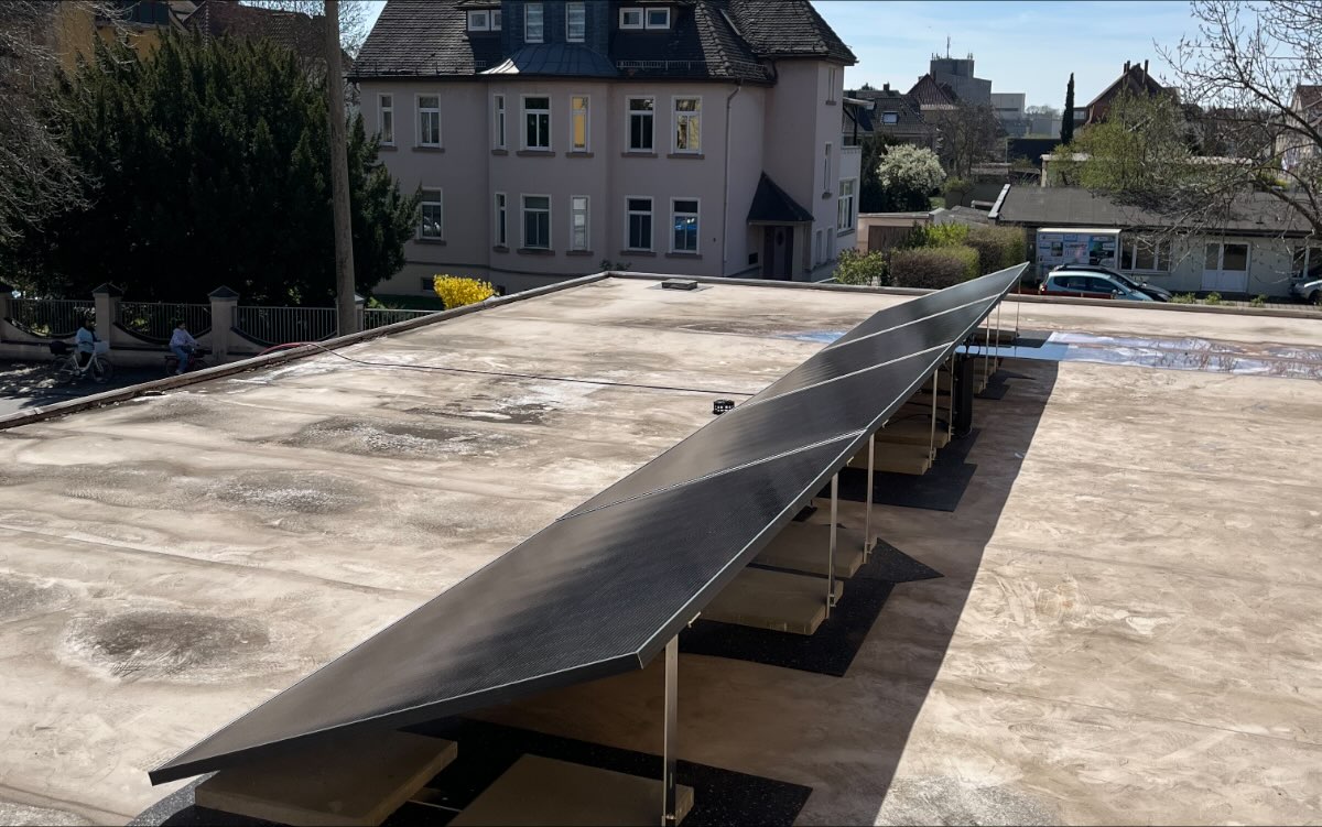 Aufgeständerte Modulreihe auf einem Flachdach, gehalten von Ballastplatten ohne Durchdringung der Dachhaut