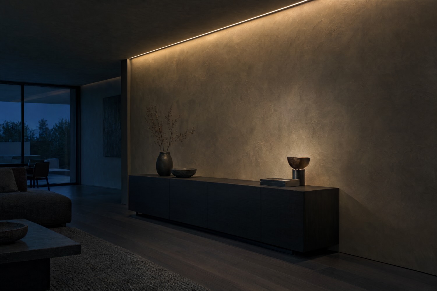 Gespachtelte Wand im Streiflicht einer Lichtvoute, davor ein dunkles Sideboard