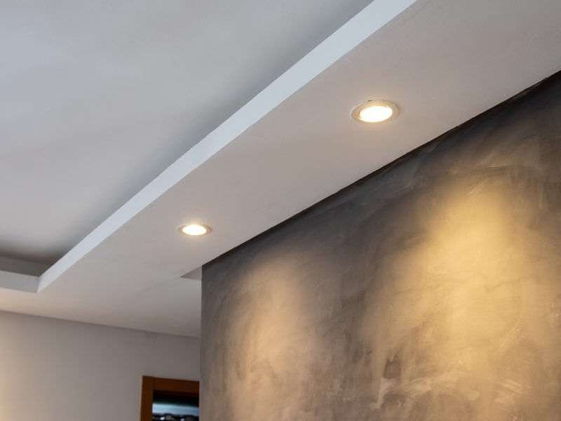 Grau gespachtelte Wand, von Einbauspots in einer abgehängten Decke angeleuchtet